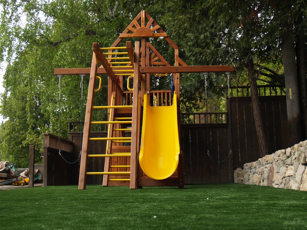 Artificial grass installed in a playground area in a backyard with a